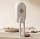 Nuzzo 3-in-1 electric pet spa brush in white with misting button, massage bristles, and a hanging loop.
