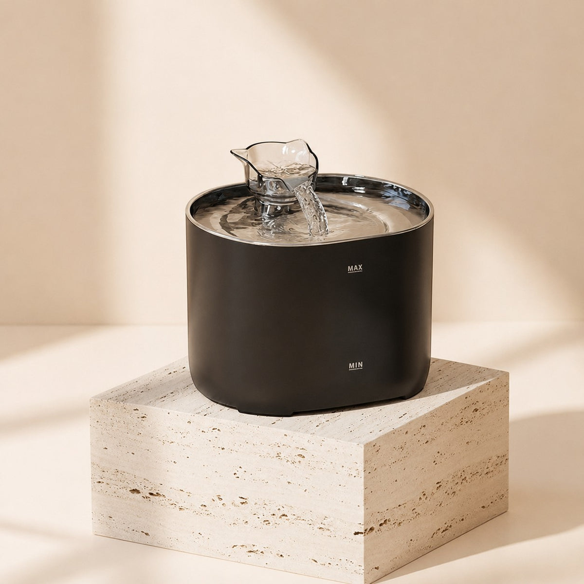 Nuzzo PureFlow black smart pet fountain with flowing water on a stone pedestal against a neutral background