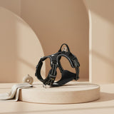 Nuzzo ReflectPro black dog harness with reflective stitching and padded chest on a minimalist beige display stand.