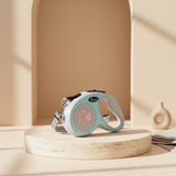 Nuzzo retractable dog leash in light blue and white with a pink paw print design on a minimalist display stand